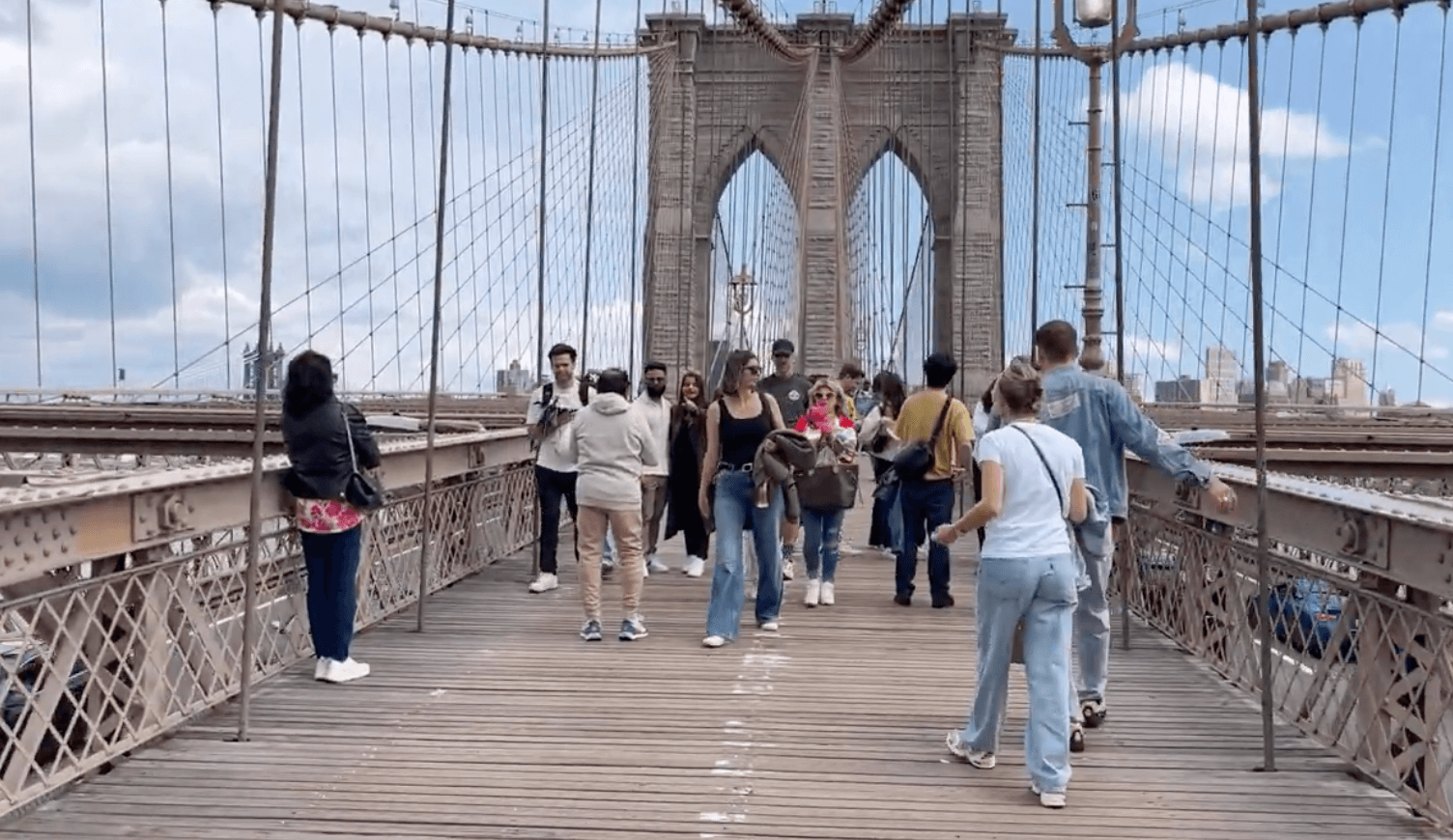 Pedestrians walking across the Brooklyn Bridge's wooden promenade